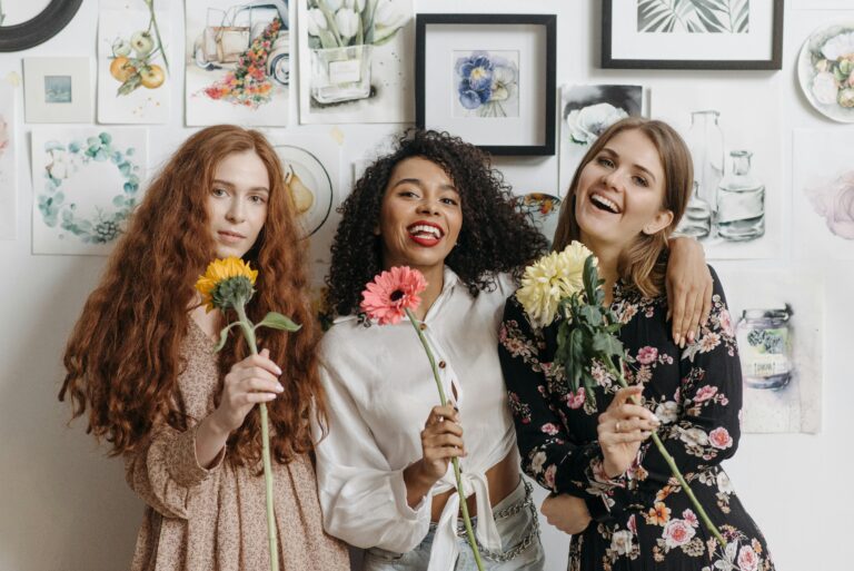 Three people with curly hair, wavy hair, and straight hair each hold a flower