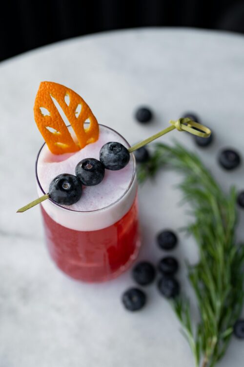 blueberry and rosemary drink An overhead shot of a blueberry and rosemary drink garnished with an orange peel