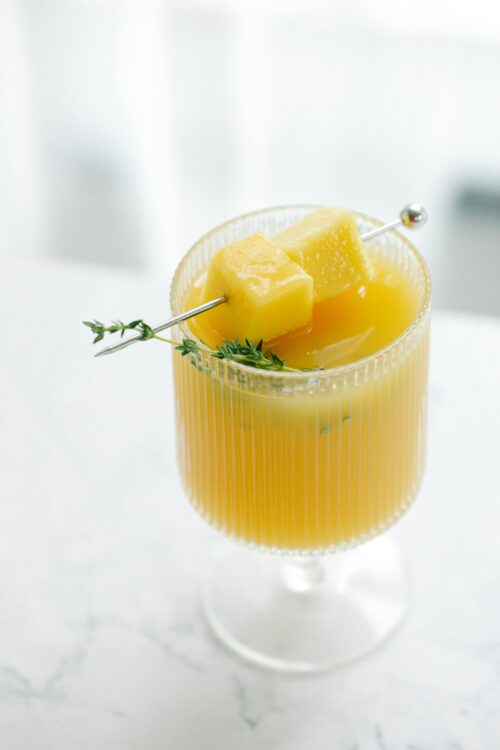 pineapple ginger fizz A small cocktail glass with a pineapple ginger fizz drink in it garnished with pineapple