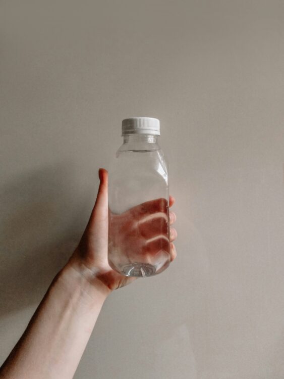 DIY Vinegar and Water Solution A person holding up a clear bottle of water and vinegar solution, which is used to clean makeup brushes