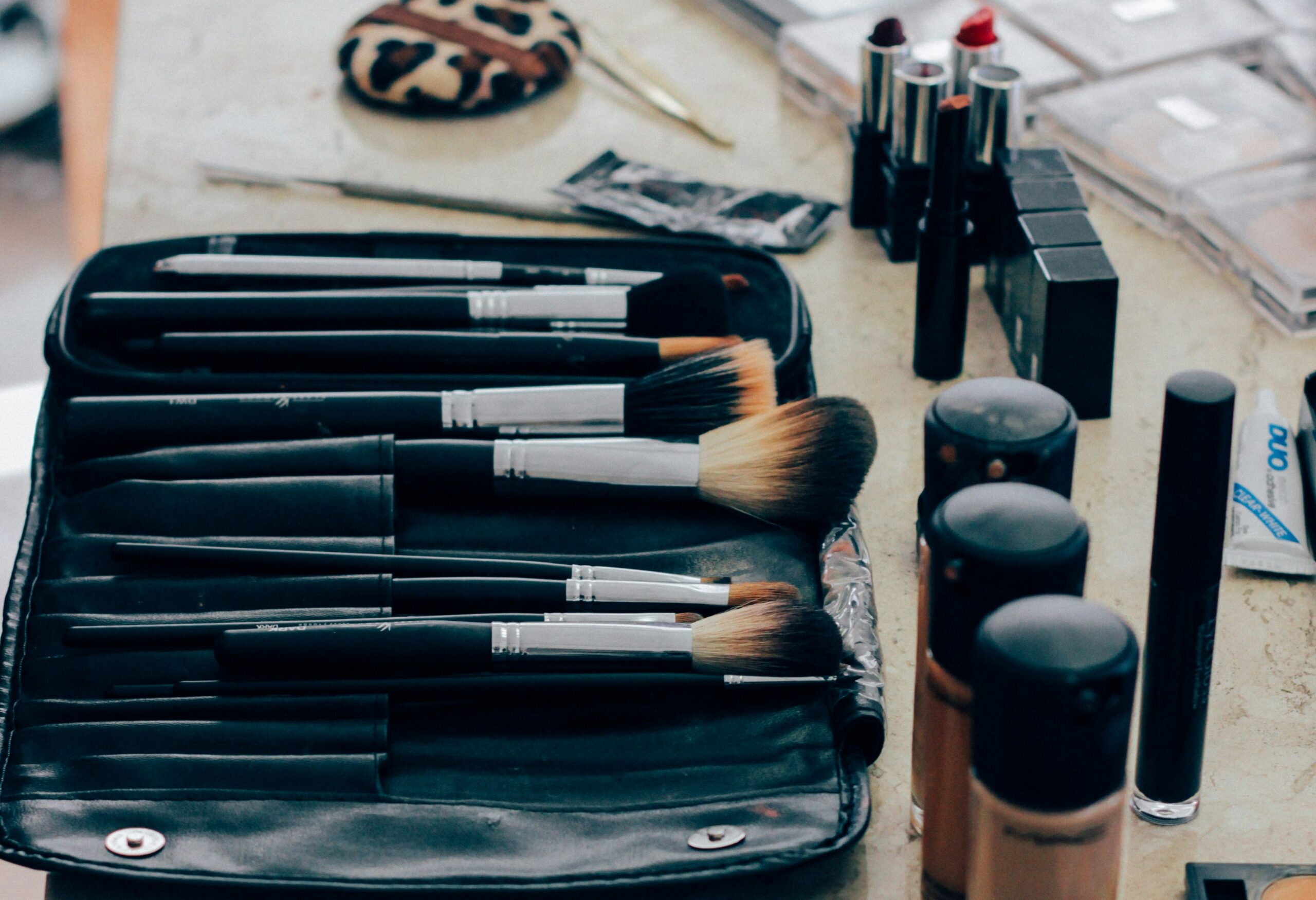 A shot of makeup brushes in an open pouch with foundation and other makeup around