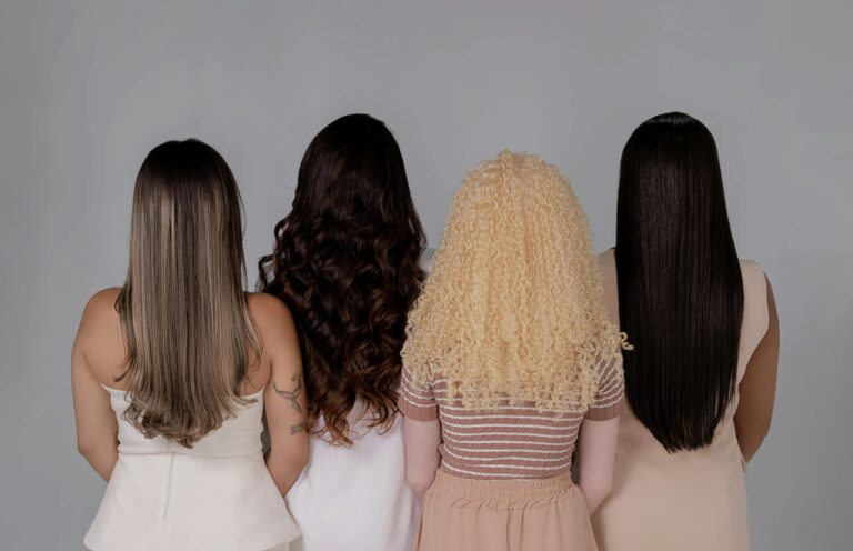 A back shot of four people with long, frizz-free hair