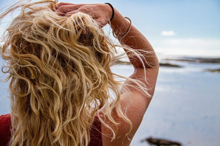 Back shot of a person with long black hair as they stare out into the sea